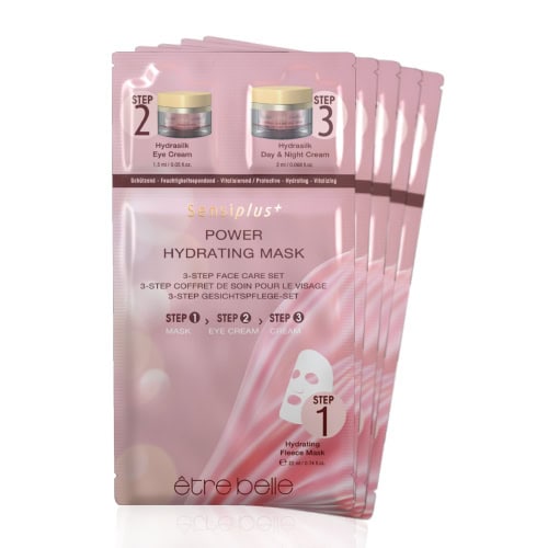 Close-up of pink facial mask sachets and skincare creams for hydration.